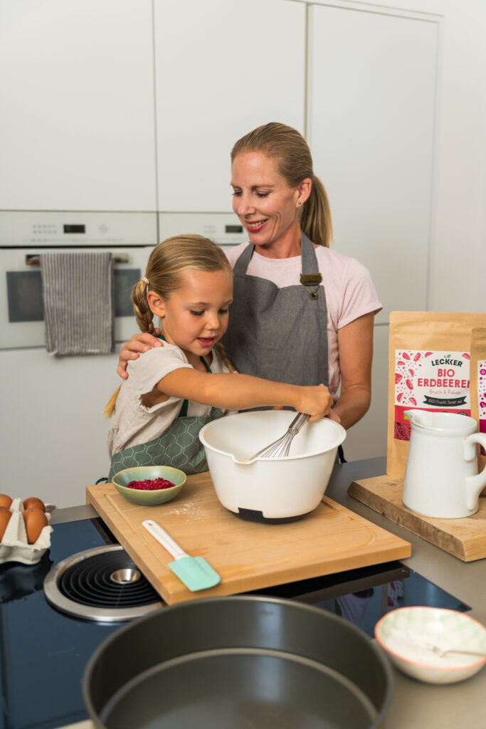 Kind sitzt in der Küche mit gefriergetrockneten Himbeeren
