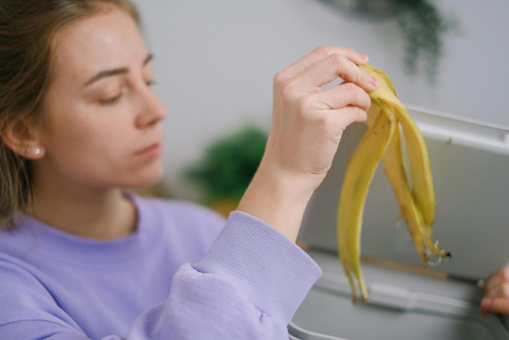 Eine Frau wirft Bananen in den Müll